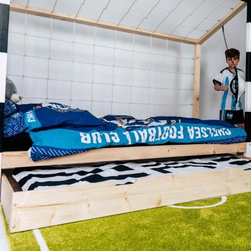 Chłopiec w pokoju dziecięcym obok łóżka bramki piłkarskiej Paco Design z pościelą w barwach klubowych