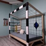Łóżko dziecięce Paco Design w kształcie bramki piłkarskiej z siatką, w pokoju o miętowych ścianach